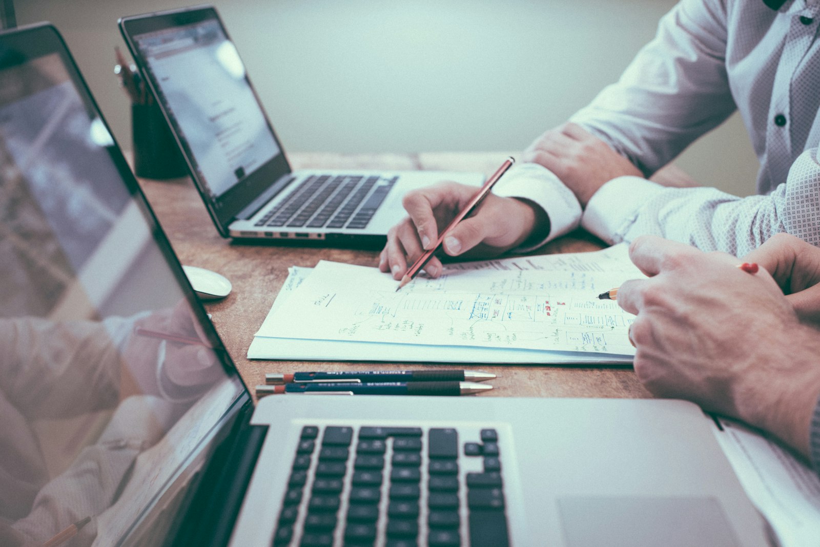Reunião de trabalho: duas pessoas revisando planos com laptops e anotações